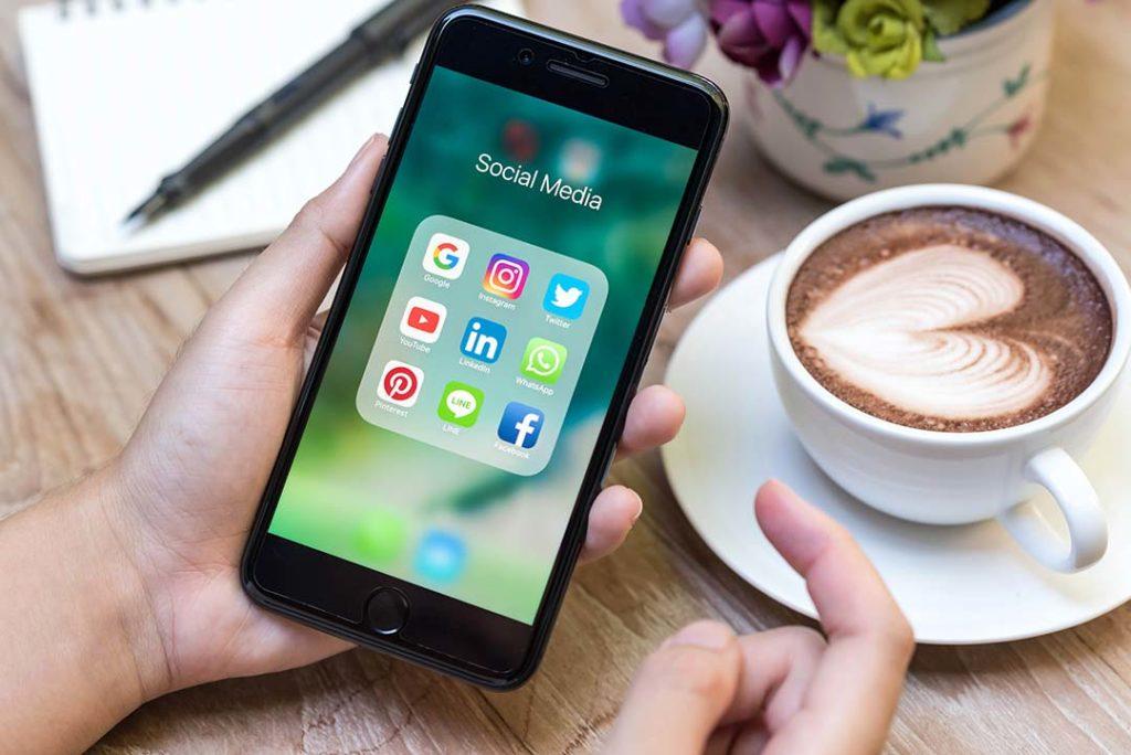 mains-smartphone-reseaux-sociaux-icones-tasse-cafe